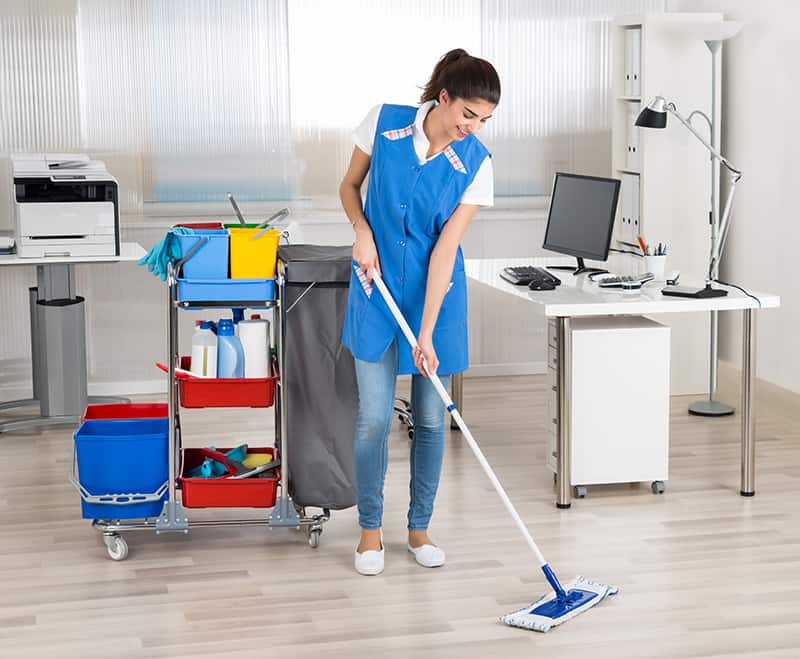 Happy Female Janitor Mopping Floor In Office